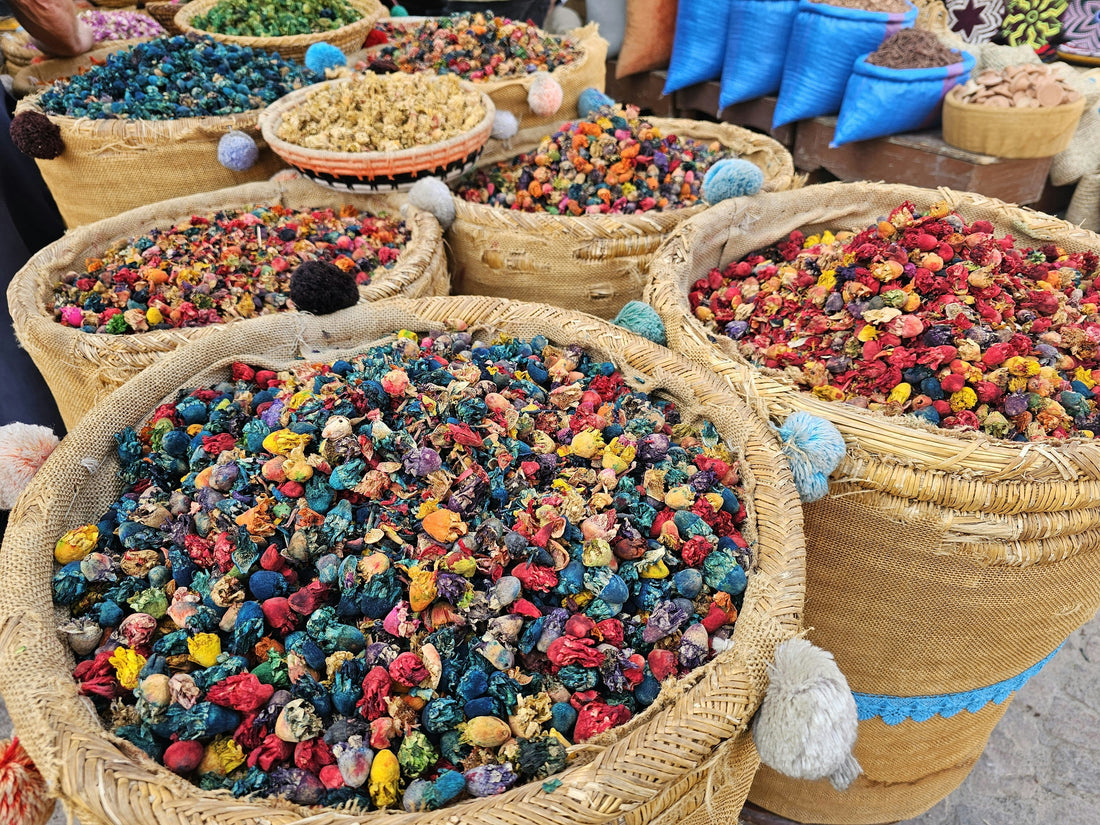 Colorful dried herbs, flowers, and tea ingredients displayed in traditional market baskets