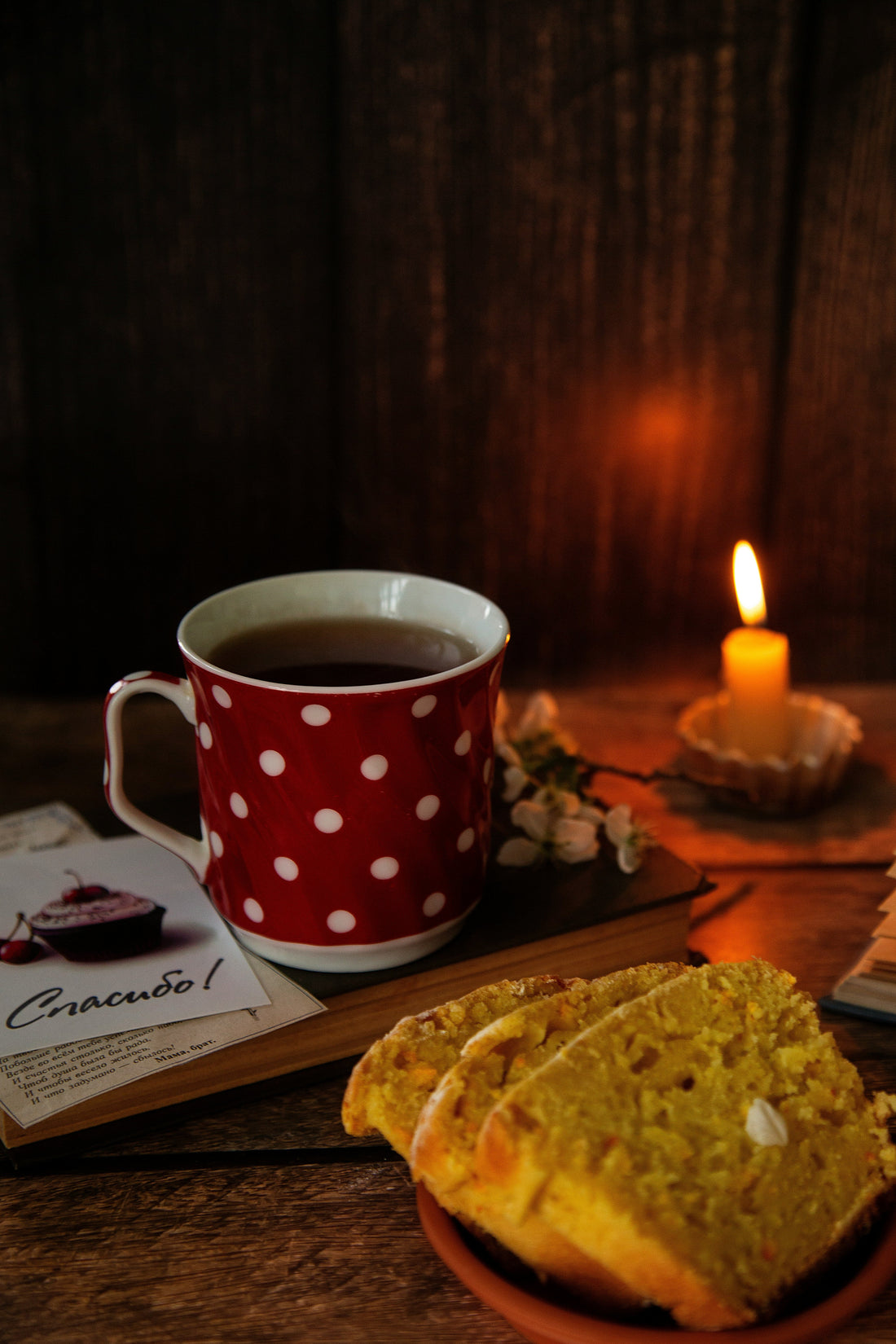 Cozy evening tea ritual with herbal tea in red polka dot mug, candle, and cookies on wooden table - perfect for relaxation and wind-down routine