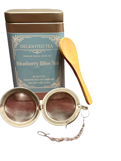 Tea canister with tea infuser and wooden spoon on a white background