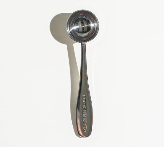 Metallic measuring spoon on a white background