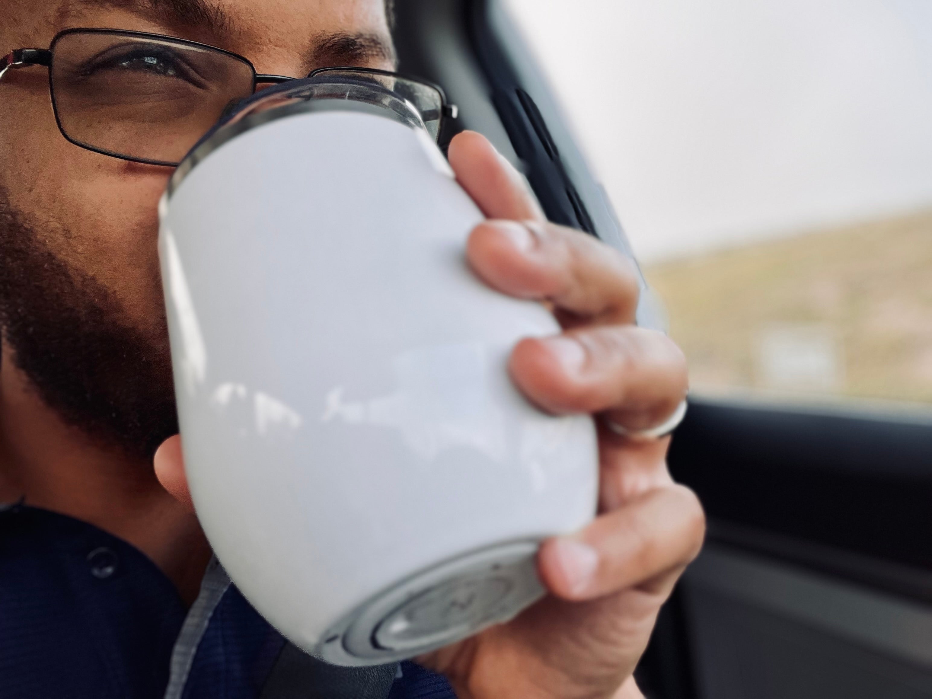 Person holding a white mug with a car interior background