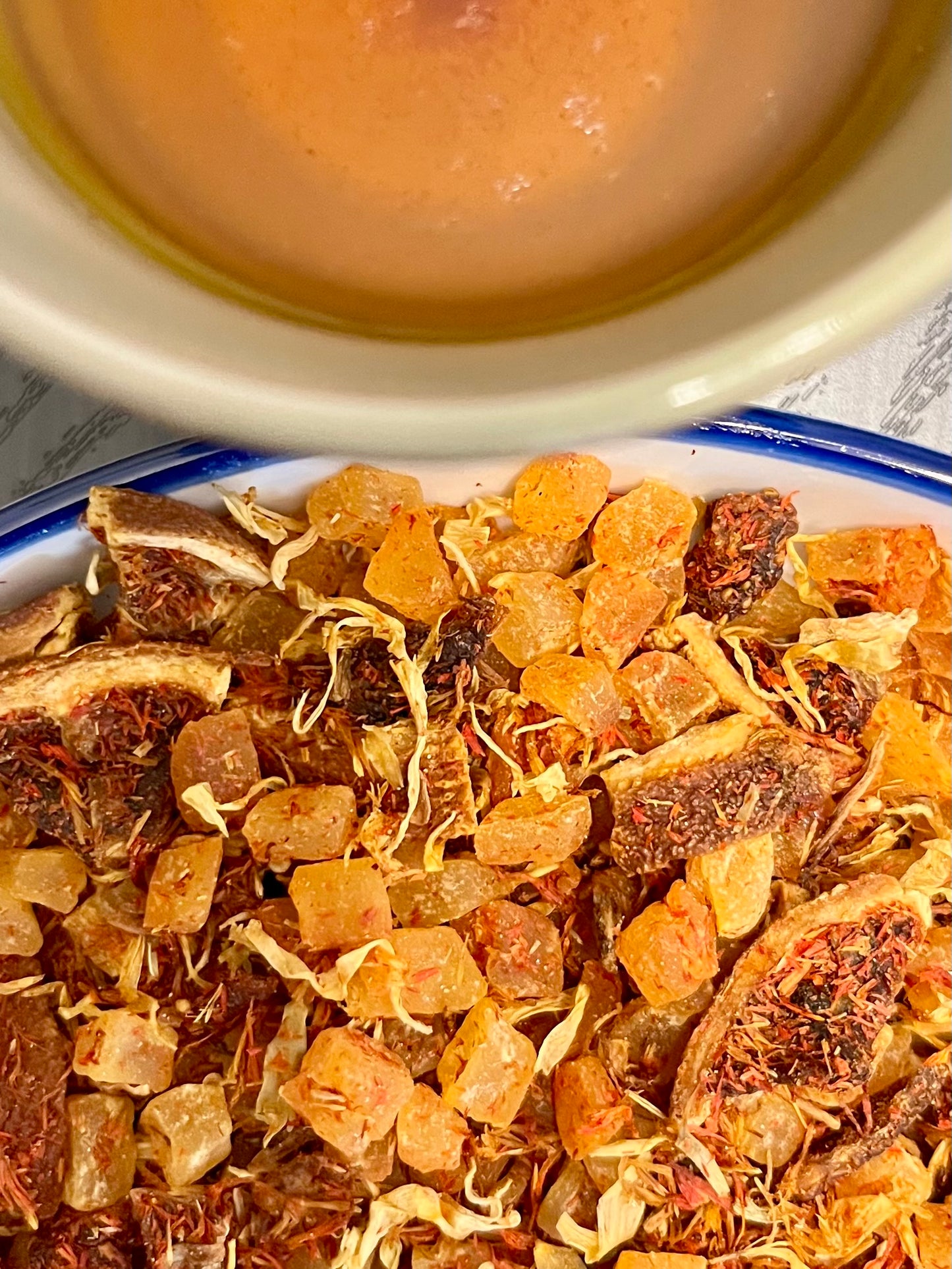 Herbal tea leaves with a bowl of liquid in the background