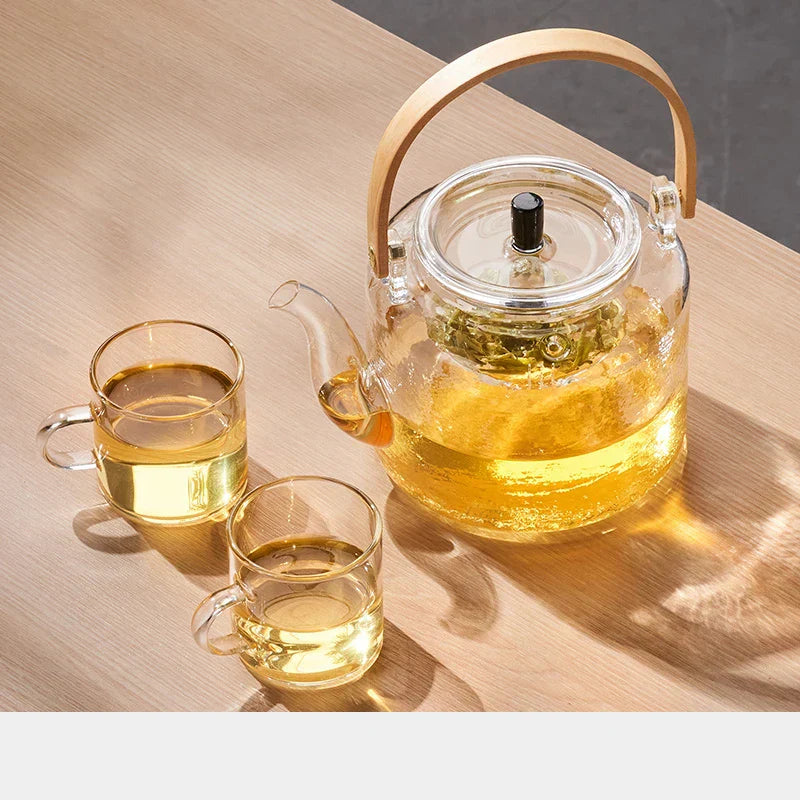 Glass teapot and cups with tea on a wooden surface