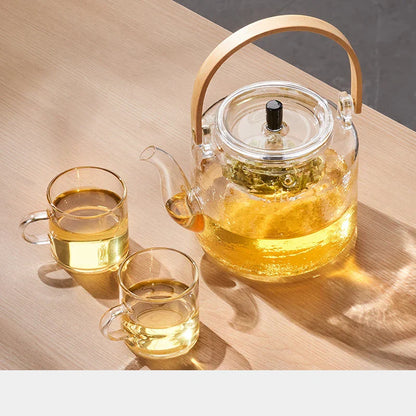 Glass teapot and cups with tea on a wooden surface