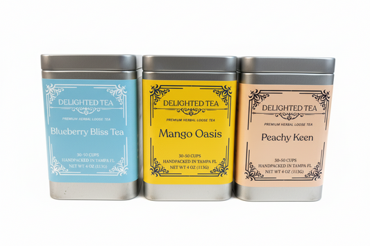 Three metal tea tins labeled 'Blueberry Bliss Tea', 'Mango Oasis', and 'Peachy Keen' from Delighted Tea on a white background.