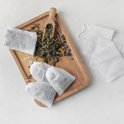Tea bags and dry leaves on a wooden tray with a light background
